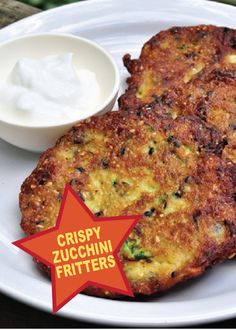 two fritters on a white plate with a small bowl of yogurt