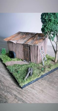 a small wooden building with a ladder next to it and a tree in the background