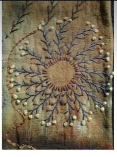 a close up of a piece of cloth with beading on it and an embroidered circle in the middle