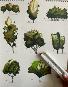 a hand holding a marker next to a drawing of trees