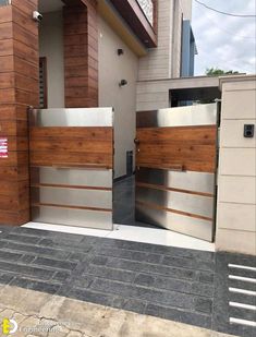 an entrance to a house with wooden panels and metal gates on the outside, in front of a brick building