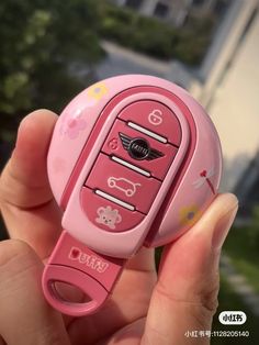 a person holding a pink cell phone with hello kitty stickers on it's side