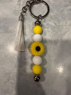 a yellow and white keychain with a tassel hanging from it's side