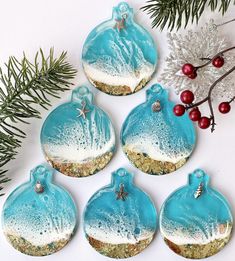 six blue and white christmas ornaments next to evergreen branches