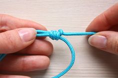 two hands are tying a blue string together