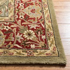 a red and green area rug on the floor with wood floors in the back ground