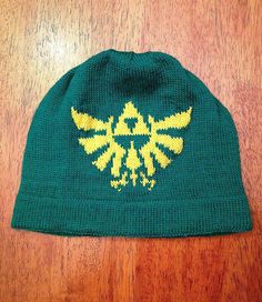 a knitted hat with the legend of zelda symbol on it sitting on a wooden surface