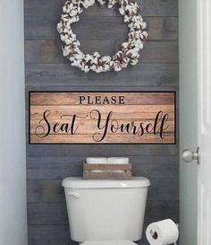 a white toilet sitting in a bathroom next to a wooden sign