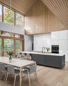 an open kitchen and dining room with wood flooring, white walls, and large windows