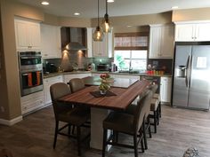 a kitchen with an island table surrounded by chairs