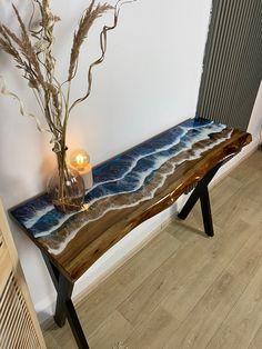 a wooden bench sitting on top of a hard wood floor next to a vase filled with flowers