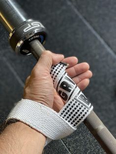 a hand holding a silver and black gym bar