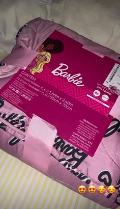 the bed is covered in pink sheets with barbie dolls on them and some tags attached to it