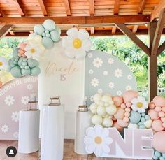 balloons and flowers decorate the backdrop for a baby's first birthday party