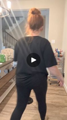 a woman in black shirt and leggings standing on wooden floor next to stairs