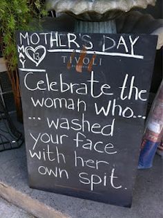 a mother's day sign on the side of a building in front of a potted plant