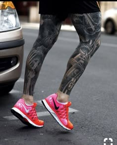 a man with tattoos on his legs is standing next to a car and wearing pink sneakers