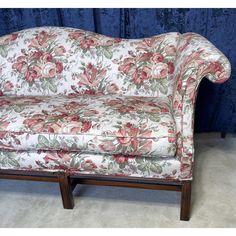 a floral couch sitting on top of a white floor next to a blue curtained wall