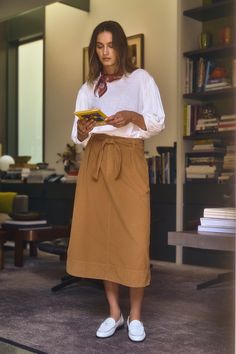 A woman stands in a room holding a book Corduroy Skirts, Belted Midi Skirt, Velvet Tees, Cami Shirt, Mens Loungewear, Corduroy Skirt, Sweater Sale, Romper Dress, Soft Hand