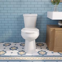 a white toilet sitting in a bathroom next to a blue and white tiled floor with flowers