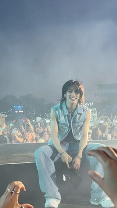 a woman sitting on top of a stage with her hands in the air and people behind her