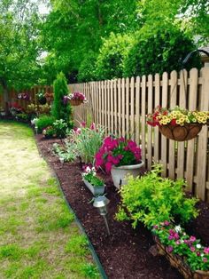 a garden filled with lots of flowers next to a wooden fence