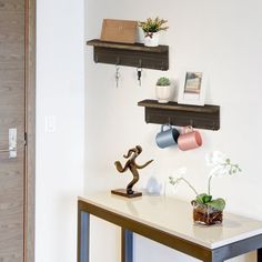 two shelves on the wall above a table with flowers and vases sitting on it