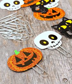 three halloween themed paper clips on a wooden table with pumpkins and jack - o'- lanterns