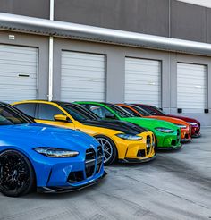 a row of different colored cars parked in front of garage doors