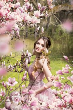 a beautiful young woman standing in front of pink flowers