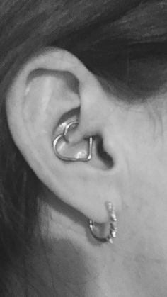 a woman's ear is shown with two silver rings