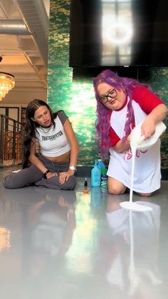 two women sitting on the floor in front of a tv