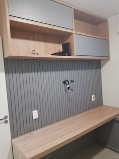 a wooden bench sitting under a shelf next to a white refrigerator in a room with gray paneling