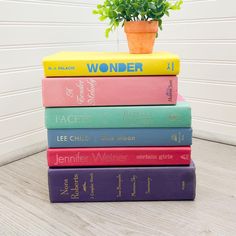 a stack of books sitting on top of a wooden table next to a potted plant