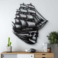 a black and white wall clock with a pirate ship on it's face next to a potted cactus