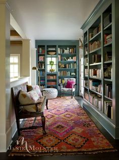 a living room filled with lots of bookshelves next to a couch and chair