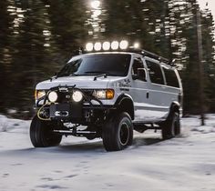 a white truck driving down a snow covered road with lights on it's headlamps