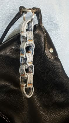 a black purse with a chain attached to the inside of it on a blue surface