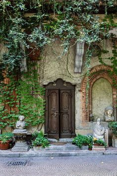 an old building with ivy growing on it's walls and two statues in front