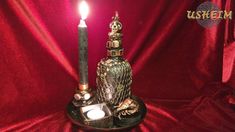 a lit candle sitting on top of a table next to a glass container with an owl