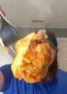 a man is holding up a fork with some food on it