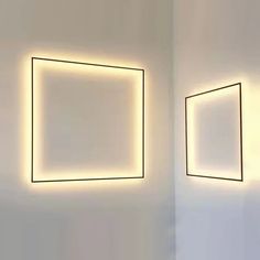 two square lights are hanging on the wall next to each other in an empty room