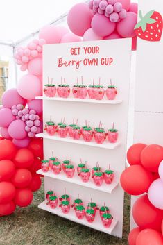 strawberry cupcakes and strawberries on display in front of a sign that says get your berry own cup