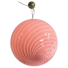 a pink lamp hanging from the ceiling with a light bulb on it's end