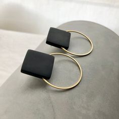 two gold hoop earrings with black onyxite stone in front of a white background