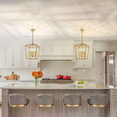 a kitchen with white cabinets and gray stools next to a center island in the middle