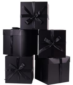 four black boxes with ribbons and bows are stacked on top of each other, one has a bow