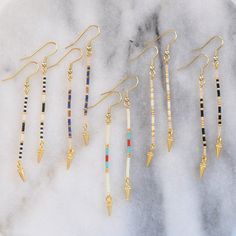 Edgy minimalism at its finest. These simple, long beaded stick earrings in a lean linear shape are just the right thing when you want a subtly cool accent. A tiny gold spike finishes the look with don't-mess-with-me edge. beaded gold-plated pin with tiny glass seed beads gold-plated stainless steel earwire hooks lead-free and nickel-free gold-plated spike charm plastic earring back 3 inches long packaged on a logo kraft card in a clear resealing bag Simple Bead Earrings, Long Beaded Earrings, Pebble Jewelry, Diy Earrings Easy, Homemade Bracelets, Stick Earrings, Beaded Earrings Diy, Plastic Earrings, Beading Techniques