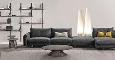 a modern living room with grey couches and two lamps on the wall above them