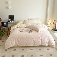 a bed with pink sheets and pillows in a room next to a desk, chair and window